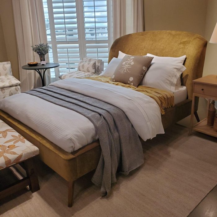 Cumming home decor expert A cozy bedroom featuring a comfortable bed with soft pillows and a warm duvet, soft lighting, and perhaps a bedside table